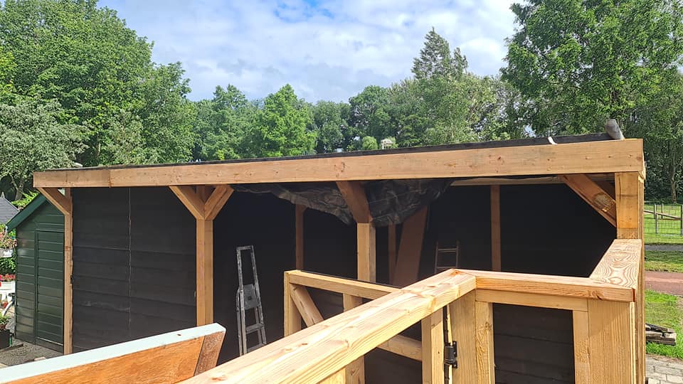 Houten overkapping met zwarte planken in aanbouw