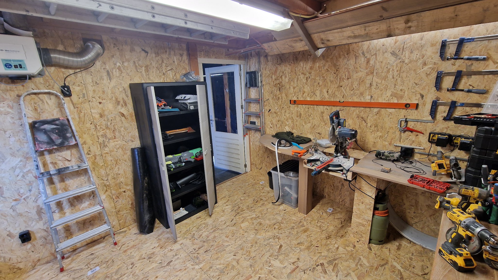 Werkruimte met gereedschap, zaagtafel en wanden van OSB-platen